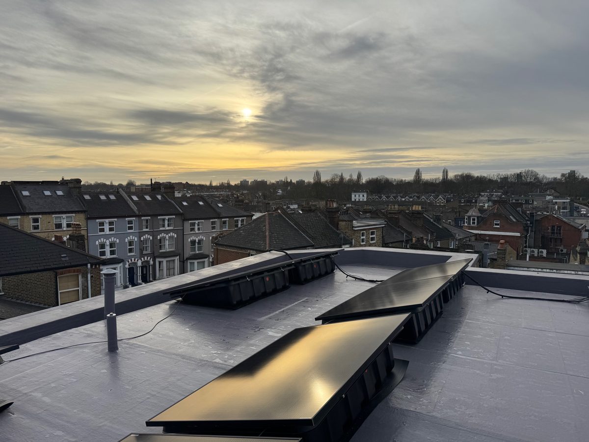 Completed Hafer Road roof with solar panels and Battersea skyline at sunset.